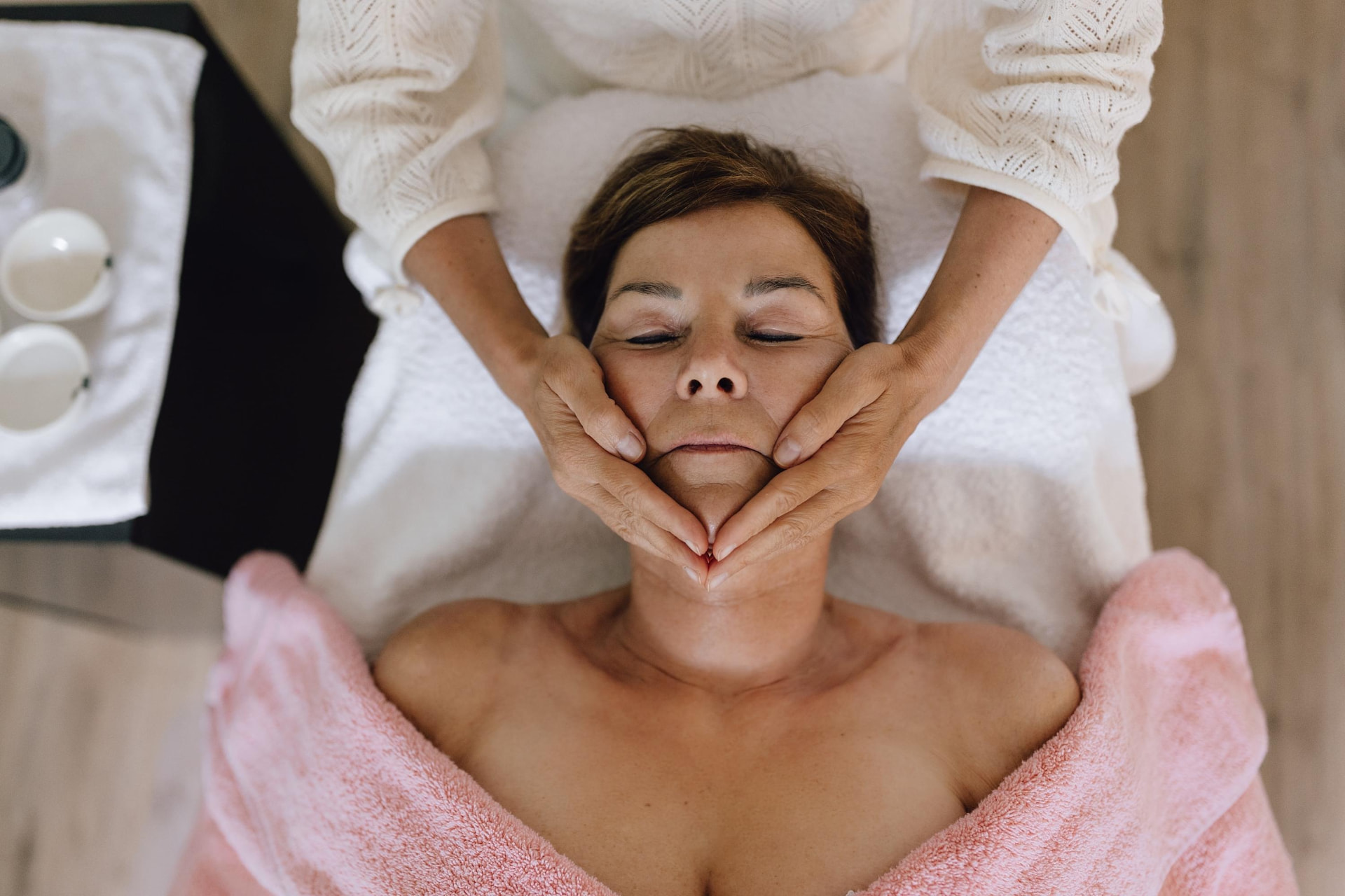 Gesichtsmassage von oben: Hände umfassen sanft Kinn und Wangen der Kundin